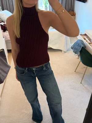 Vinröd ribbad halternecktop - Snygg vinröd ribbad halternecktop med hög krage och ärmlös design. Aldrig använd.