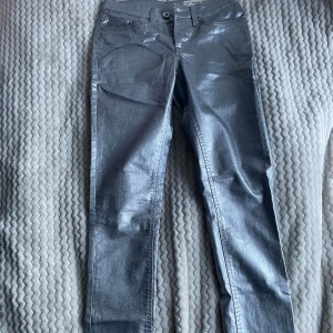 silver jeans - Säljer ett par glansiga silverfärgade jeans från Esmara i skinny fit. Byxorna har klassisk femficksdesign, normal midja och smal passform hela vägen ner. Aldrig använd eller tvättad. Helt perfekt för fester och halloween.
