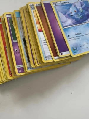 Bunt Pokémonkort original - Säljer en stor bunt Pokémonkort med klassisk gul ram och olika motiv. Blandade typer och energikort, perfekt för samlare eller spel. Korten har den ikoniska blå baksidan med Pokéboll och Pokémon-logga. .