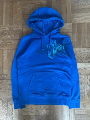 Blå hoodie från O'Neill med tryck - Blå hoodie från O'Neill med stort tryck på bröstet och mönstrad insida i huvan. Klassisk känguruficka framtill och dragsko i huvan. Perfekt för en chill och avslappnad stil.