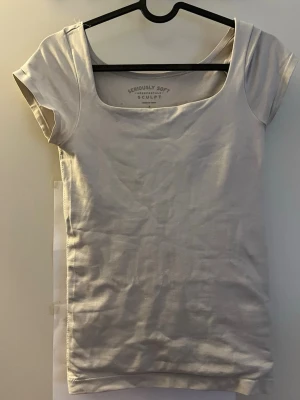 Vit kortärmad topp från Aeropostale - En basic vit topp från Aeropostale med korta ärmar och bred, fyrkantig urringning. Tillverkad i mjuk bomull som känns skön mot huden. Perfekt att styla med jeans eller kjol för en clean look.