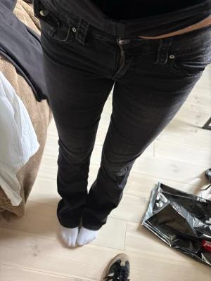 Svarta bootcut jeans med ficklock - Snygga svarta jeans med bootcut passform och coola ficklock bak. Jeansen har klassisk femficksdesign, bälteshällor och dragkedjegylf. Materialet är denim med lätt tvättad look som ger en avslappnad vibe.
