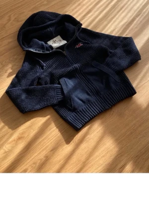 Mörkblå stickad hoodie Hollister - Skick 9/10, modellen är 184cm~78kg, hoodien är kort och ganska tajt i armarna, storlek S
