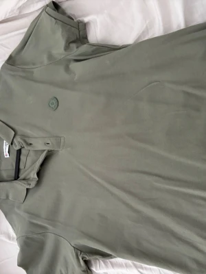Grön pikétröja från Moncler - Snygg grön pikétröja från Moncler med klassisk krage och knappslå framtill. Tröjan har Moncler-logga broderad på bröstet och är tillverkad i ett bekvämt bomullsmaterial.  Passar storlek L!!!!!!!