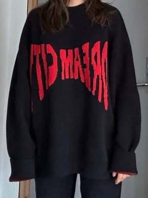 Svart stickad tröja med röd text - Text 'DREAM CITY' på framsidan. Oversized passform. Perfekt för dig som gillar streetstyle och statement-plagg. Passar S-XL