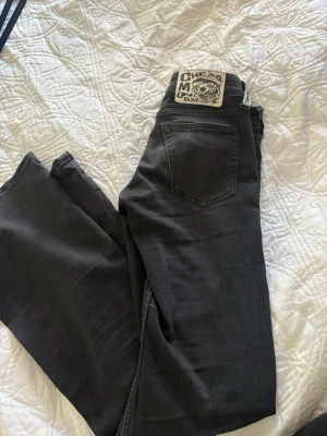 Svarta Cheap Monday jeans - Snygga svarta jeans från Cheap Monday med klassisk femficksdesign och raka ben. Jeansen har en tydlig logga på bakfickan och är tillverkade i stretchigt denimtyg för en bekväm passform.