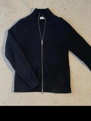 Svart stickad selected homme ziptröja  - Svart stickad tröja med hel dragkedja från selected homme. Köpte tröjan för 799 kr och säljer den för lägre. Använt tröjan 3 ggr och blev o nöjd med den. Tveka inte o buda !