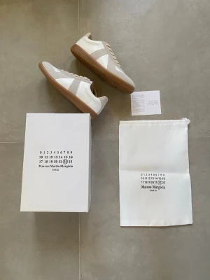Maison Margiela sneakers vita/beige - Maison Margiela sneakers i vitt och beige läder och mocka med klassisk gummisula. Snygg minimalistisk design med diskreta detaljer och ikonisk logotyp på insidan. Den ljusa färgen och den beiga sulan är perfekt inför sommaren☀️. Allt på första bilden ingår‼️ om ni har några funderingar tveka ej att fråga ‼️