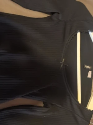 Svart ribbad långärmad topp Vero Moda - Svart långärmad topp från H&M  med ribbad struktur. Toppen har en rund halsringning och är tillverkad i ett stretchigt material som sitter snyggt på kroppen. Perfekt att styla med jeans eller kjol.