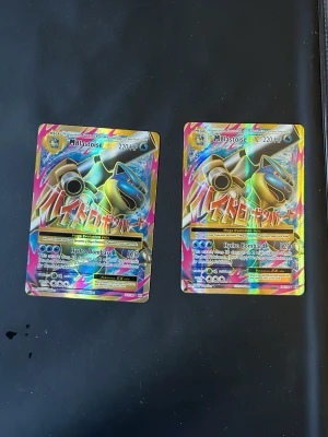 2 st M Blastoise EX Pokémonkort - Två stycken holografiska M Blastoise EX Pokémonkort med färgglad och glansig design. Motivet visar Blastoise med texten 'Hydro Bombard' och 220 HP. Baksidan har klassiskt blått Pokémon-tryck med Pokéboll. Perfekt för samlare eller Pokémon-fans.