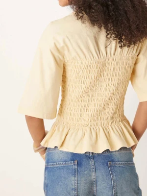 Beige blus med smock och volang - Supersöt beige blus med smockad midja och volangkant nertill. Toppen har halvlånga ärmar och rund halsringning. Perfekt att styla med jeans eller kjol för en trendig look. Tagg kvar