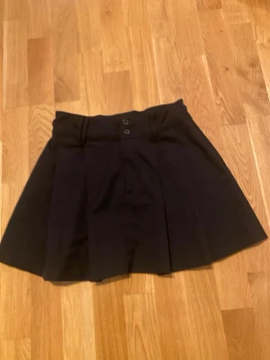 Svart kortkjol - Sljer en svart kortkjol från H&M. Den har knappar framtill och kjolen är utsvängd! Skriv gärna till mig om ni har några frågor!