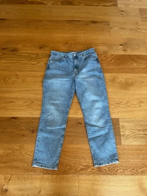 Ljusblå raka jeans i klassisk modell - Säljer ett par ljusblå jeans med rak passform och klassisk femficksdesign. Jeansen har normal midja och stängs med knapp och dragkedja. Perfekta för en avslappnad stil och tillverkade i denim. Inga synliga loggor eller märken. W29 L29
