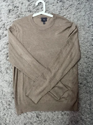 Beige tunn tröja från H&M - Säljer en beige tunn långärmad tröja från H&M i slim fit-modell. Tröjan har rund halsringning och är tillverkad i ett mjukt, lätt material som passar perfekt för lager-på-lager. Enkel och stilren design som funkar till det mesta. Är storlek S men passar nog bäst för M. 