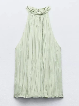 Ljusgrön plisserad halterneck topp - Säljer en ljusgrön plisserad halterneck topp med hög krage och ärmlös design. Toppen har ett elegant fall och stängs med knapp i nacken. Perfekt för dig som vill ha en stilren och trendig look.