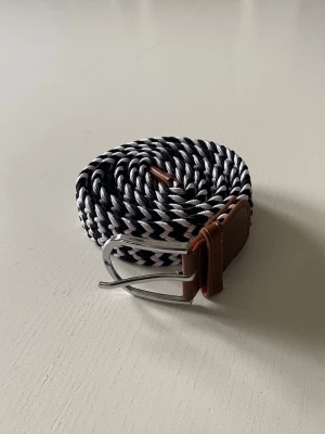 Flätat svart vitt bälte  - Snyggt randigt bälte i färgerna svart o vitt. Bältet är endast använt någon enstaka gång och är helt utan defekter:) Bältet har en klassisk design och passar till många olika stilar. Skriv vid frågor och kolla gärna in min profil för fler bälten!
