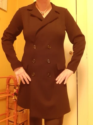 Svart dubbelknäppt spring coat från Prettylittlething  - Stilren svart rock med dubbelknäppning och klassisk krage. Rocken har långa ärmar, två fickor med lock och sex stora svarta knappar framtill. Passformen är rak och materialet ser ut att vara ett kraftigare tyg som passar till kyligare dagar. LIGHTWEIGHT.  Length: 85 cm, under arm width: 46 cm, arm leng: 57 cm. Storlek: 44 eller lite 46.