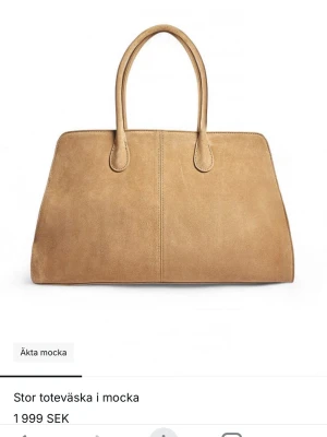 Stor beige toteväska i mocka - Säljer en stor och rymlig toteväska i äkta beige mocka. Väskan har två långa handtag, guldfärgad dragkedja och flera innerfack för smart förvaring. Perfekt för dig som vill ha plats för allt du behöver under dagen. Enkel och stilren design som passar till det mesta.