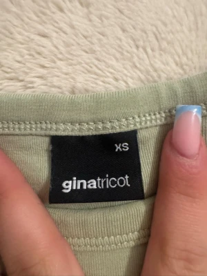 Grön t-shirt från Gina Tricot XS - Ljusgrön t-shirt från Gina Tricot i storlek XS med tryck 'Surf Vibes Honolulu' framtill. T-shirten har rund halsringning och korta ärmar. Perfekt för en avslappnad och trendig stil.