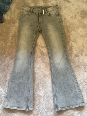 Grå flare jeans med vintagekänsla - Säljer ett par gråa flare jeans med lätt tvättad look från Weekday, W27 L30 