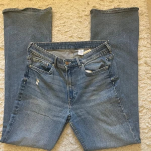 H&M Bootcut jeans med hög midja  - Bootcut jeans från H&M i ljusblå tvätt med hög midja. Jeansen är välanvända men i bra skick. Materialet är jeans och passformen är loose med en snygg bootcut-stil. Perfekt för dig som gillar retrovibbar. Säljer dessa jeans eftersom de är för stora för mig. 