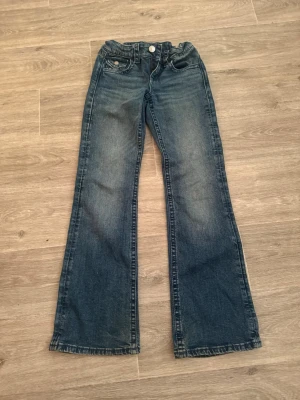 Blåa bootcut jeans med rosett där bak🎀 - Blåa jeans från Ginatricot storlek 152 bra skick inga skador några småfläckar (går mest troligen att tvätta bort) används några antal gånger.