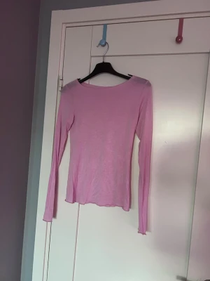 Ljusrosa långärmad topp - En enkel och stilren ljusrosa långärmad topp med rund halsringning. Tunn och mjuk i materialet, perfekt att styla lager på lager eller bära som den är. Passformen är slim och toppen har en lätt stretchig känsla.