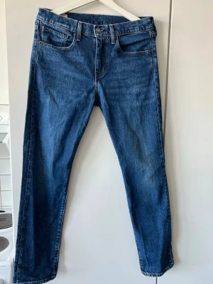 Levi's 502 blå raka jeans - Klassiska blå Levi's 502 jeans med rak passform Jeansen har en snygg mellanblå tvätt, bruna sömmar och läderpatch bak i midjan. Tillverkade i slitstark denim. Nypris: 1299kr 