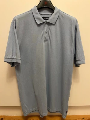 Ljusblå piké från Take Off, 2XL - Ljusblå pikétröja från Take Off i 100% bomull. Klassisk modell med krage, korta ärmar och knappar framtill. Har några missfärgningar (se bild).