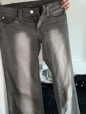 Gråa straight fit jeans från MONDAY - Säljer ett par gråa straight fit jeans från MONDAY med slitna detaljer och ljusa partier framtill. Jeansen har klassisk femficksmodell, bälteshällor och knappgylf. Materialet är 70% bomull, 28% polyester och 2% elastan för lite stretch.