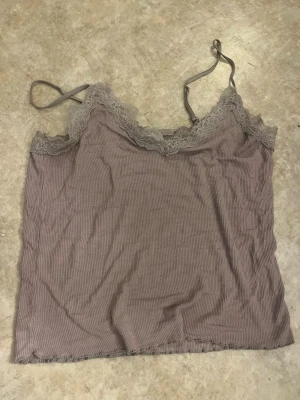 Ljuslila ribbad linnetopp med spets - Säljer en ljuslila ribbad linnetopp med tunna axelband och spetsdetaljer längs urringningen. Toppen har en croppad passform och är perfekt för lager på lager. Materialet känns mjukt och stretchigt.