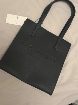 Ted Baker Handväska - Svart Ted Baker handväska, oanvänd! Höjd: 25cm Längd: 25cm Vidd: 11cm Handtag: 17cm