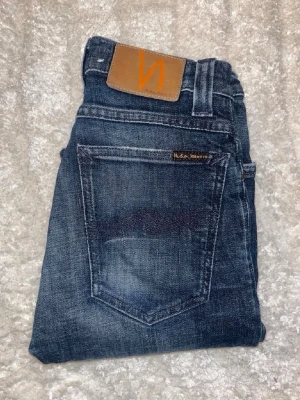 Nudie jeans - Mörka jeans från Nudie Jeans, modell High Kai men snygg ljusare kontrast. Midja 31cm, längd 107cm. JAG SKICKAR EJ FLER BILDER NÄR JAG BÄR JEANSEN! för bättre inblick i passformen rekommenderar jag att googla på modellnamnet. För storleksguide kolla måtten noggrant då jeansen alltid kan vara uppsydda heller krympta och jag ej tar emot returer :) s6,4