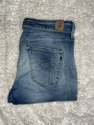 Replay jeans  - Säljer ett par blå Replay jeans. OBS jeansen har ett hål på ena knät. Midja 36cm, längd 99cm. JAG SKICKAR EJ FLER BILDER NÄR JAG BÄR JEANSEN! för bättre inblick i passformen rekommenderar jag att googla på modellnamnet. För storleksguide kolla måtten noggrant då jeansen alltid kan vara uppsydda heller krympta och jag ej tar emot returer :) s6,1
