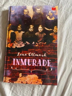 Inmurade av Lena Ollmark - En spännande bok med titeln 'Inmurade' av Lena Ollmark. Omslaget har en mörk, mystisk design med illustration av barn och tegelvägg. Boken handlar om mystiska händelser på en skola och hemligheter i källaren. Perfekt för dig som gillar skräck och mysterier.
