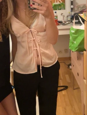 Ljusrosa topp med snörning - Trendig ljusrosa omlottopp med smala axelband och djup v-ringning. Toppen har dekorativa snörningar framtill som ger en unik look. Perfekt att styla med jeans eller kjol för en cool vibe.