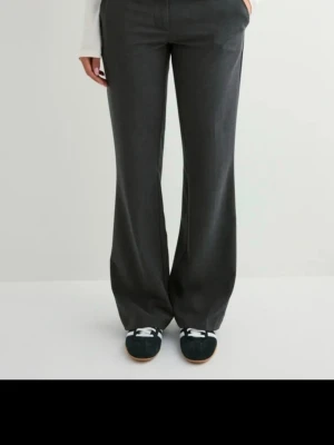 Snygga Lågmidjade kostymbyxor från Nelly  - Jättesnygga grå kostymbyxor från Nelly som tyvärr är för små för mig. Byxorna är utsvängda och har fickor fram. Råkade dra bort prislappen men de är aldrig använda och har inga defekter. Passar mig bra i längden som är 164💕 