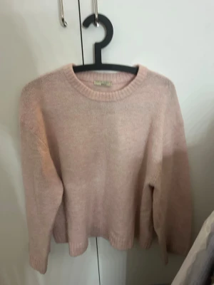 Ljusrosa stickad tröja från ginatricot - Ljusrosa stickad tröja från ginatricot med rund halsringning och långa ärmar. Tröjan har en enkel och clean design med ribbstickade muddar vid hals, ärmslut och nederkant. Perfekt för att skapa en soft och chill look. I storlek Xs 