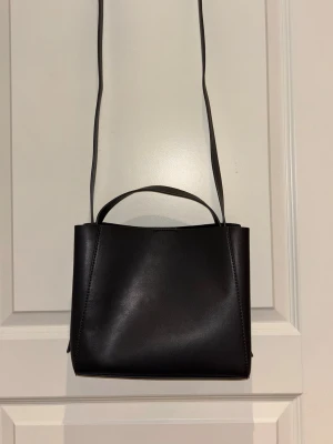 Väska från Gina Tricot - Säljer min mörkgrå väska från Gina Tricot som jag endast har använt 2 gånger. Den är i väldigt fint skick och har inga synliga skador.  Väskan är rymlig och enkel i modellen. Den har både kort handtag och lång axelrem, så den går att bära på olika sätt. Inuti finns ett innerfack med dragkedja för mindre saker.  – Märke: Gina Tricot – Färg: Mörkgrå – Skick: Använd 2 gånger – Axelrem + handtag – Innerfack med dragkedja  Säljer den eftersom den inte riktigt kommit till användning.  📦 Skickas snabbt