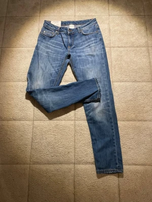 Blå slim jeans från dondup  - Säljer ett par klassiska blå jeans från dondup med raka ben och snygga slitningar. Jeansen har fem fickor, silverfärgade nitar och en liten Diesel-logga på bakfickan. Tillverkade i mjuk denim som sitter skönt hela dagen.