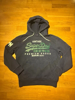 Superdry hoodie - Säljer en riktigt snygg superdry hoodie, en ganska vanlig och snygg färgkombination. Storleken är M och passformen är riktigt snygg (hör av dig om du vill ha bild). Inga defekter och svarar snabbt!