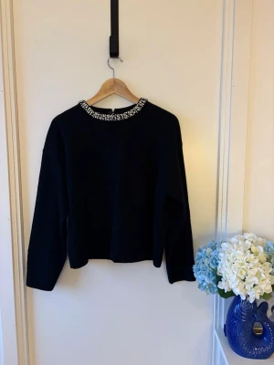 Black embellished neckline sweater / jewel collar - Elegant black sweater with a decorative rhinestone embellished neckline that gives it a subtle statement look.  Simple and classic fit with long sleeves, making it easy to dress up or down. The jeweled collar adds a touch of sparkle, perfect for dinners, events, or festive occasions.  Soft and comfortable fabric. In great condition, only used once     embellished sweater rhinestone neckline jewel collar party sweater festive sweater elegant black sweater minimal chic