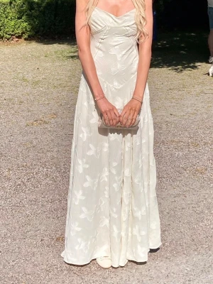 Balklänning från House of CB - Balkänning från House of CB, modell ”Seren”.  Säljer nu min klänning som har använts en gång på min studentbal.   Klänningen är krämvit/off-white med söta blomdetaljer och tunna axelband. Ryggen har en snygg snörning som gör att man kan anpassa passformen.   Skick:  använd endast en kväll! Tvättad en gång i låg värme med ett kortprogram.  Nypris $285 på House of CB:s hemsida. Med frakt blir nypriset ca 3200kr. Kan skicka bild på kvittot!    S