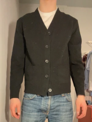 Svart premium kofta från Uniqlo, XS - Klassisk svart kofta från Uniqlo i storlek XS. Koftan har v-ringning. Jätte mjuk uniqlo premium ull och nästan aldrig använd. 