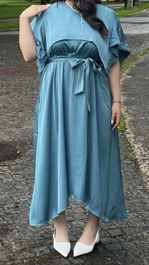 Blå/turkås långklänning  - Snygg blå långklänning, korta ärmar med spetsdetaljer och ett matchande midjeband att knyta. Klänningen har ett elegant, flytande fall och är tillverkad i ett glansigt polyestertyg som ger en lyxig känsla. Klänningen har inga skador och är använd bara en gång.