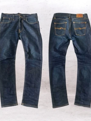 Nudie jeans, Lean Dean W29 L30 - Snygga mörkblå jeans från Nudie Jeans med klassisk femficksdesign och kontrastsömmar. Jeansen har raka ben och är tillverkade i kraftig denim. Bakfickorna har Nudie Jeans signatursöm och läderpatch i midjan. Modell Lean Dean och storlek W29 och L30. Mycket bra skick. Skicka vid funderingar eller prutning