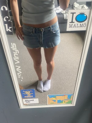 Blå jeanskjol med rå kant - Säljer en kort blå jeanskjol med rå, fransig kant nertill och klassiska fickor fram och bak. Kjolen har en normal passform och stängs med knapp och dragkedja framtill. Perfekt för dig som gillar en avslappnad och trendig stil. Kjolen är klippt själv ut ett par gamla jeans