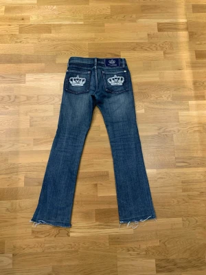 Vicktoria Beckham bootcut jeans - Super snygga Vicktoria Beckham jeans. Det är mörkblåa och är low waist bootcut. På fickornq är det fina kronors som är vita. Det är tyvärr för små för mig men waist är 37 cm och innebenslängden är 75-76 cm!💕