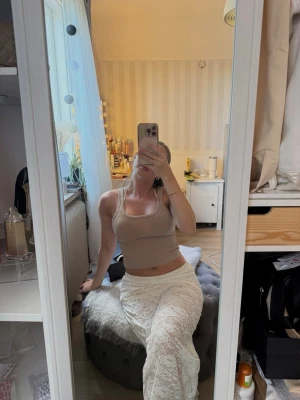 Beige ribbad linnetopp - Snygg beige ribbad linnetopp med breda axelband och rundad halsringning. Toppen är croppad och har en tight passform, perfekt att styla med höga byxor eller kjol. Enkel och stilren design som passar till många outfits.