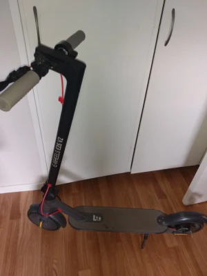 Elscooter E-Wheels E2S V2 svart - Säljer en svart elscooter E-Wheels E2S V2 med digital display på styret och gråa handtag. Scootern har en robust ram, röda detaljer och står stadigt med stöd. Perfekt för att ta sig fram snabbt i stan. Går i 30kmh. 